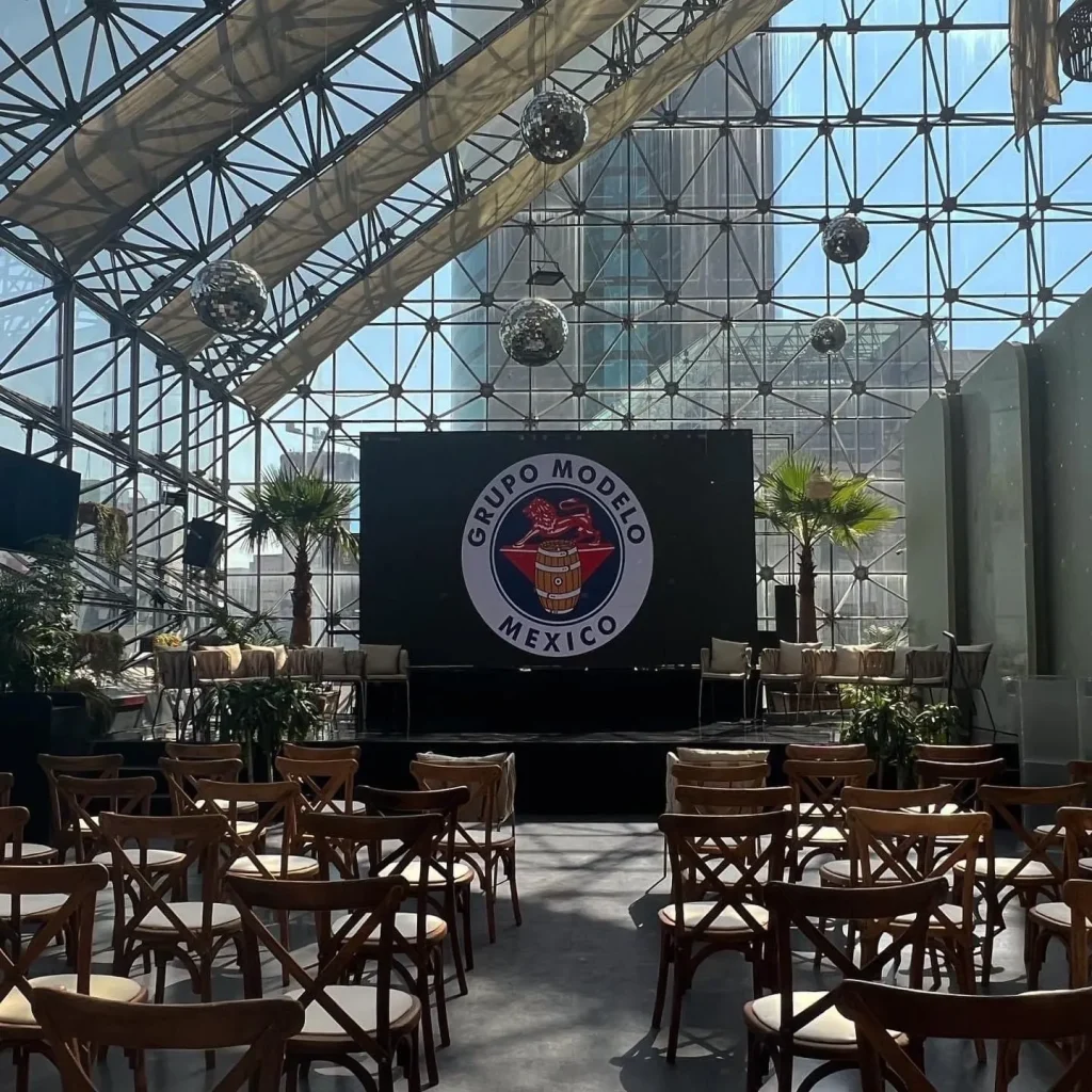 Conferencia corporativa Grupo Modelo en CDMX con sillas tiffany pantalla LED y producción al aire libre
