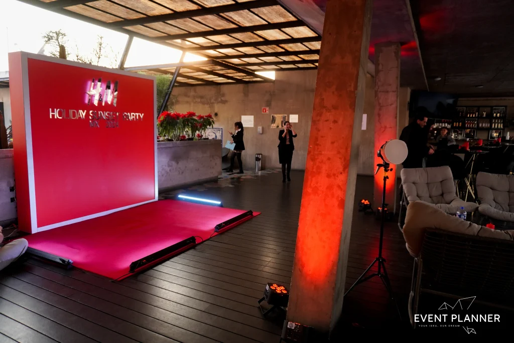 Inauguración corporativa H&M Holiday Spanish Party en terraza CDMX con backdrop rojo y producción premium