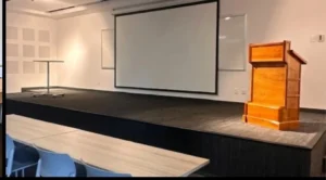 Escenario con podio de madera y pantalla de proyeccion en el Auditorio Roma 2, Roma Norte CDMX