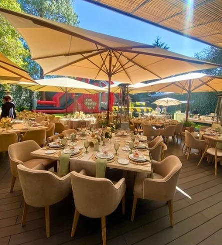 Sombrillas grandes sobre banquete con mesas redondas en jardín