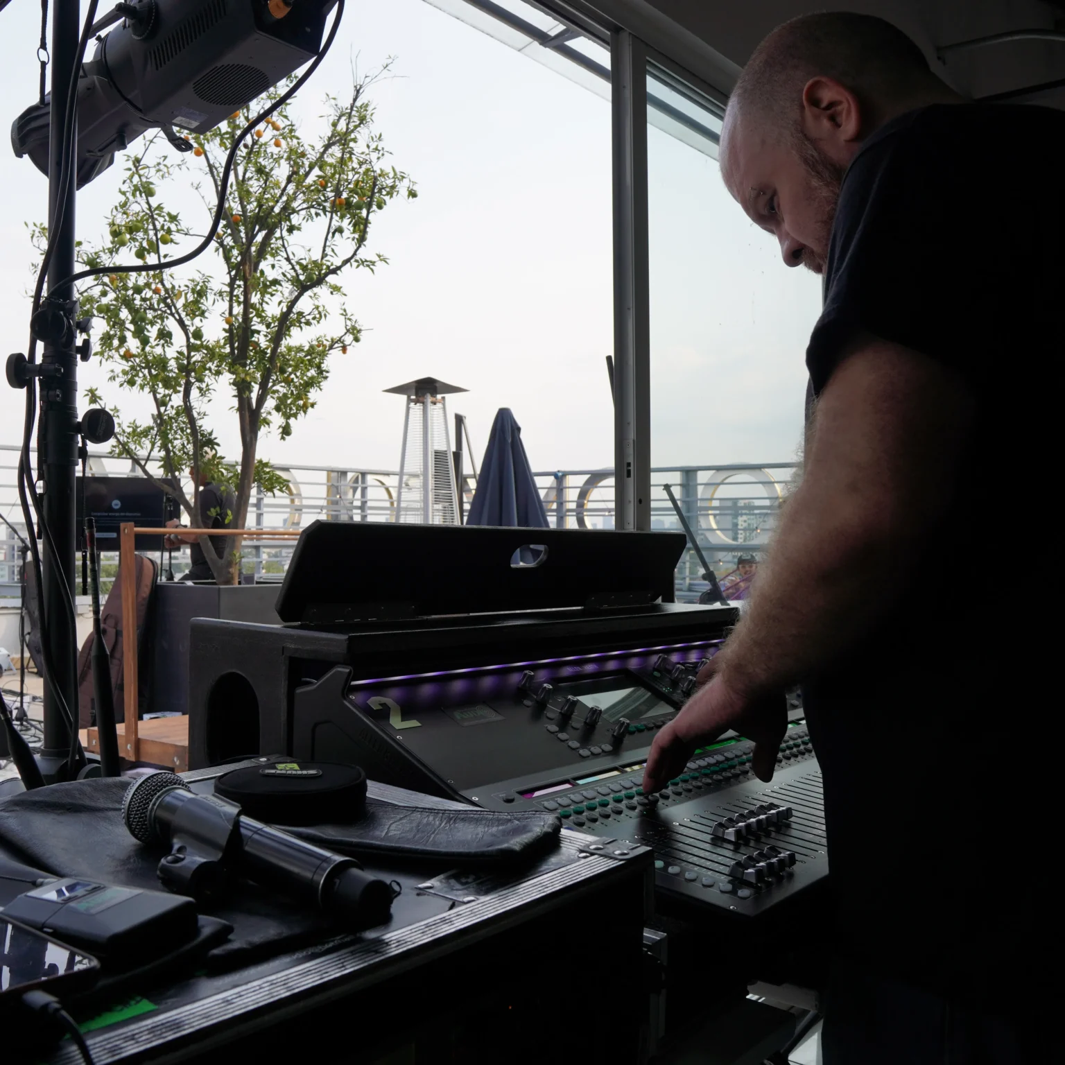 Ingeniero de audio opera la consola de sonido durante un evento en una terraza de la CDMX
