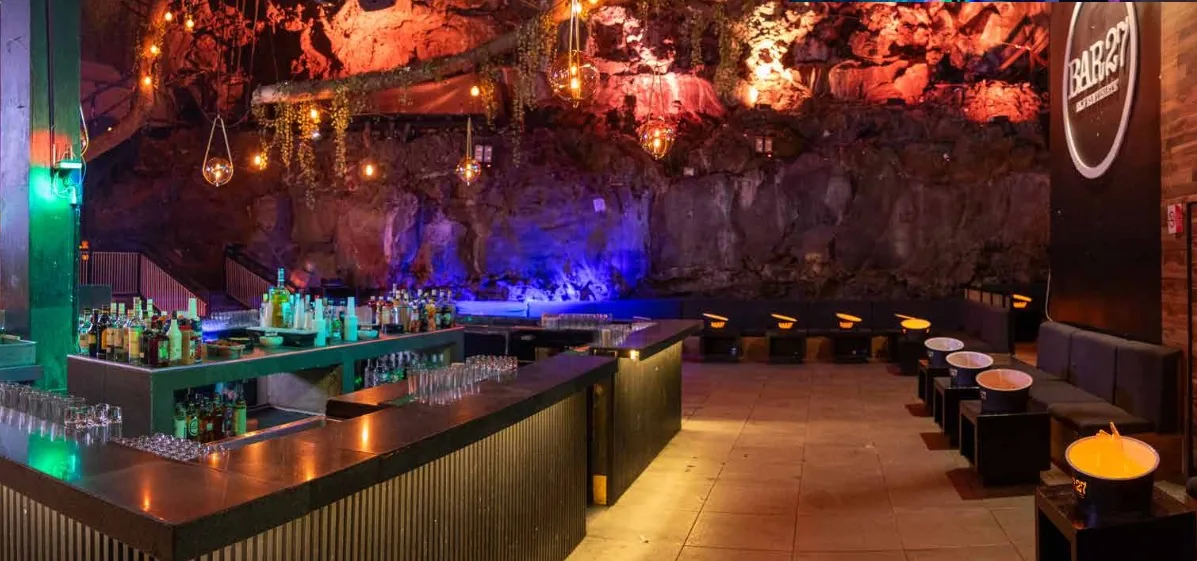 Antro Pedregal 5 — pared de roca volcánica con luces colgantes cálidas