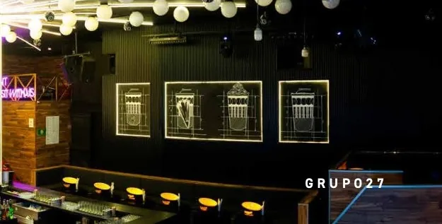 Antro Santa Fe 1 — muro con vitrinas decorativas iluminadas junto a barra con taburetes altos