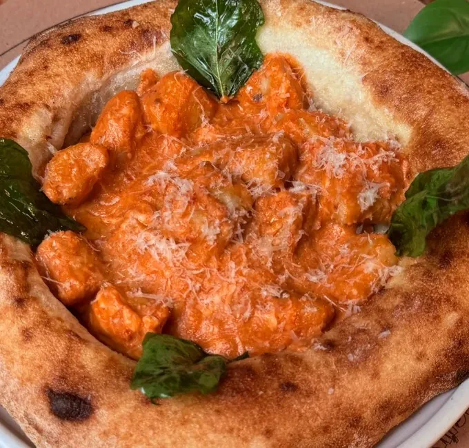 Ñoquis a la sorrentina servidos dentro de masa de pizza