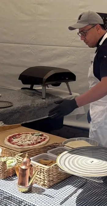 Pizzaiolo preparando pizza al momento junto al horno en un evento