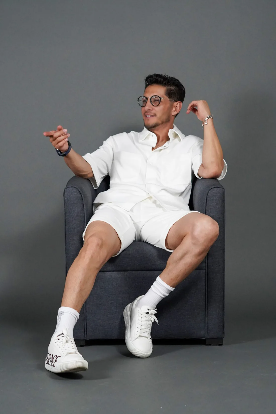 Book de fotos de hombre con look blanco en sillón de estudio