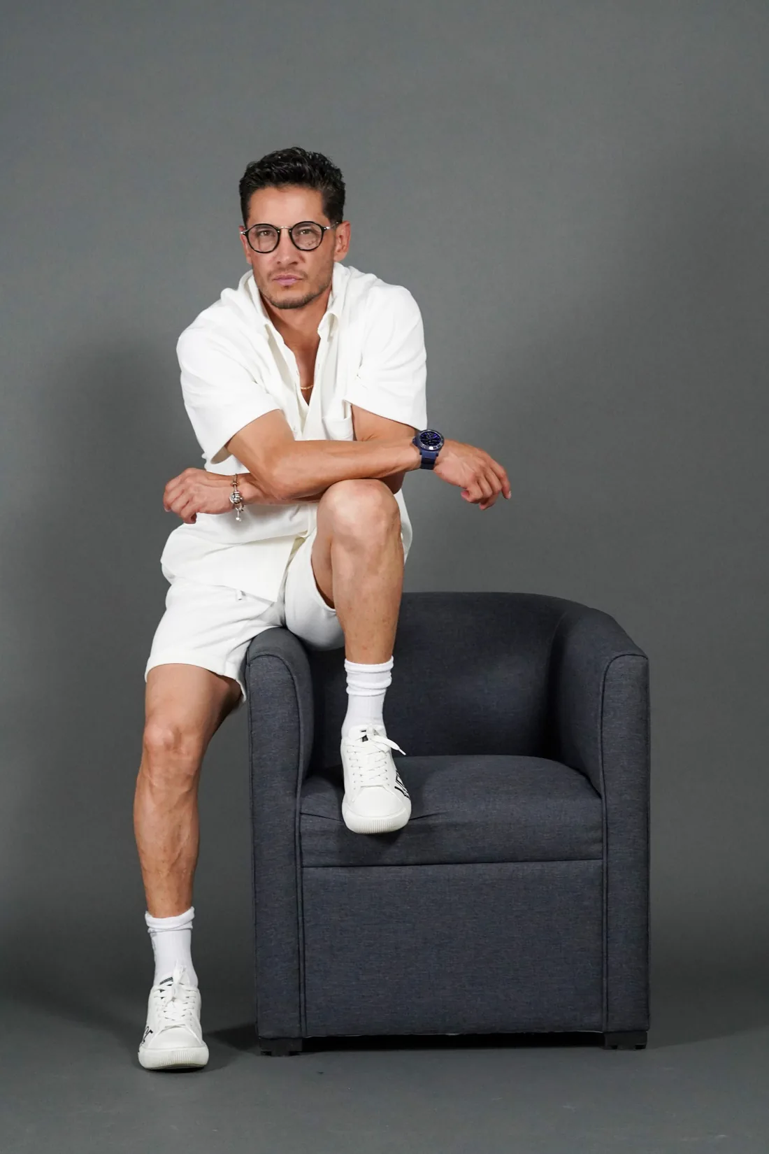 Book fotográfico de hombre sentado en sillón sobre fondo gris