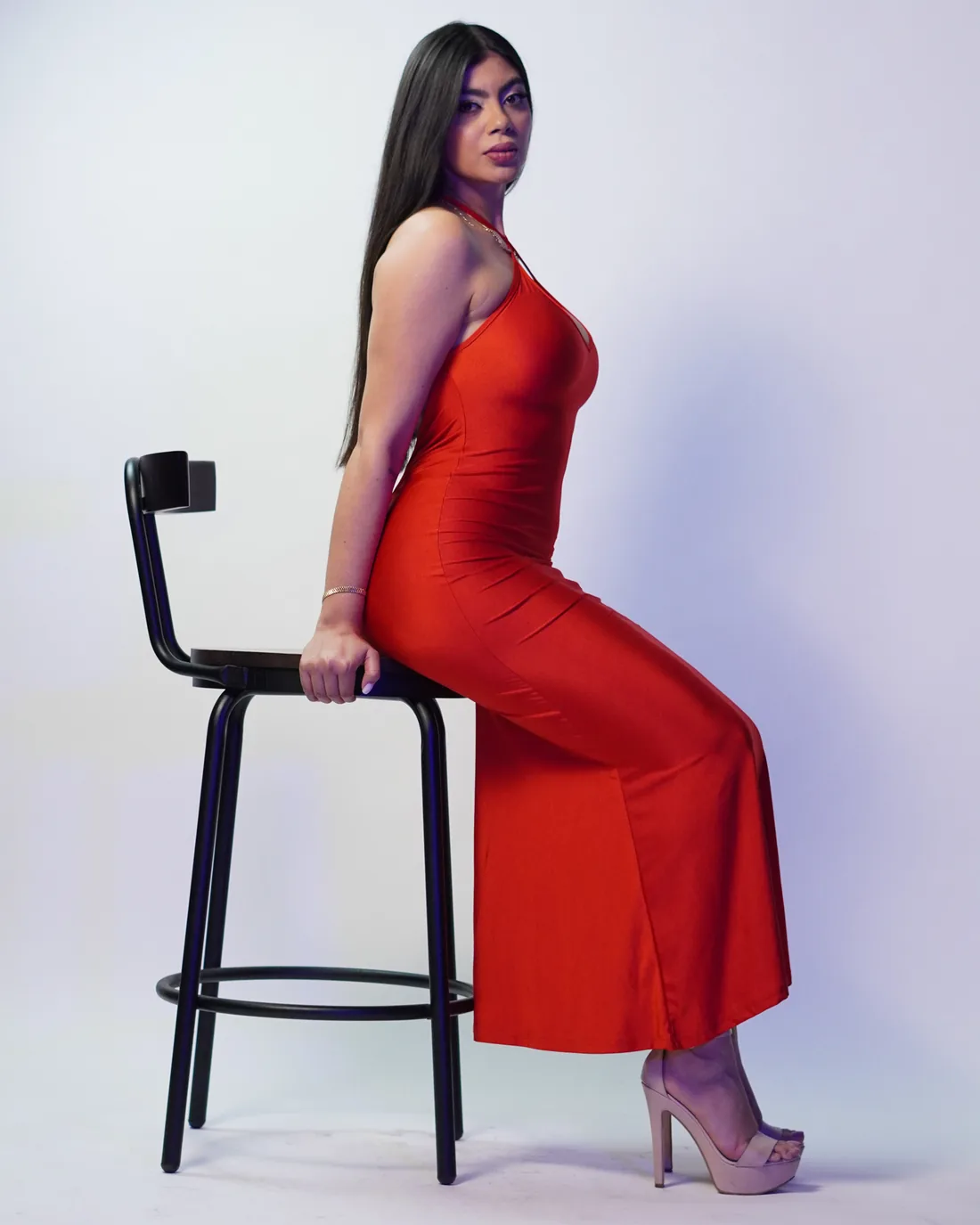 Book fotográfico con vestido rojo apoyada en banco de estudio