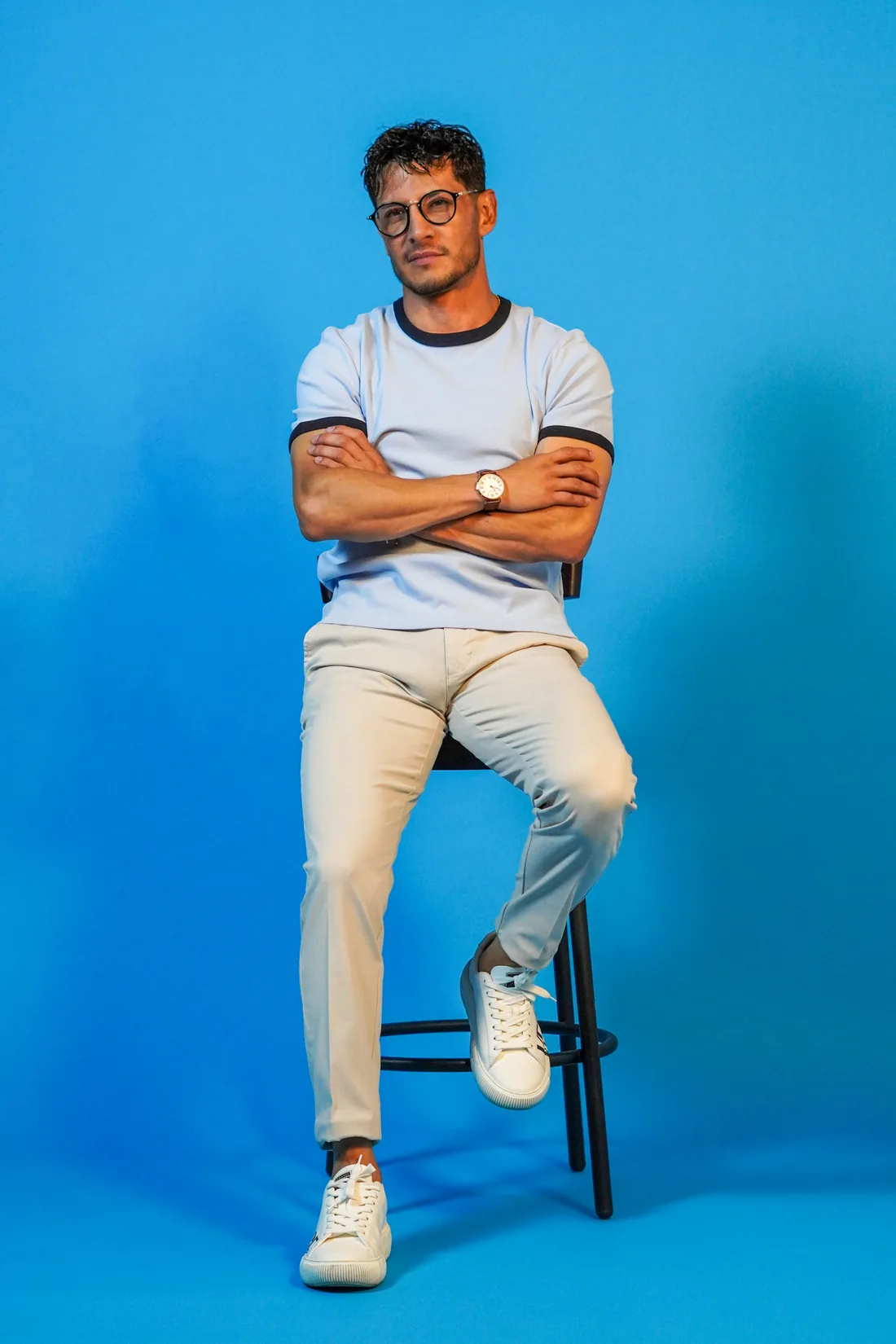 Book profesional de hombre con brazos cruzados sobre fondo azul