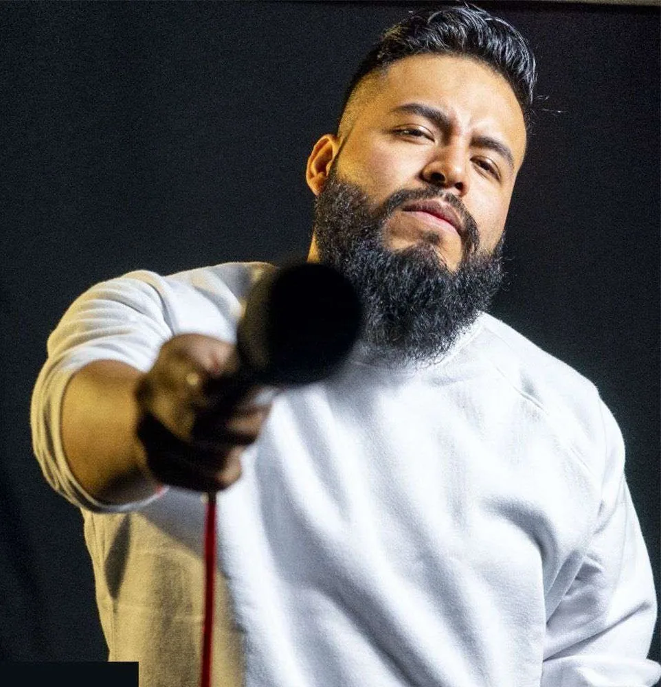 Carlos Mosco, comediante de stand up, apuntando con el micrófono en retrato de estudio