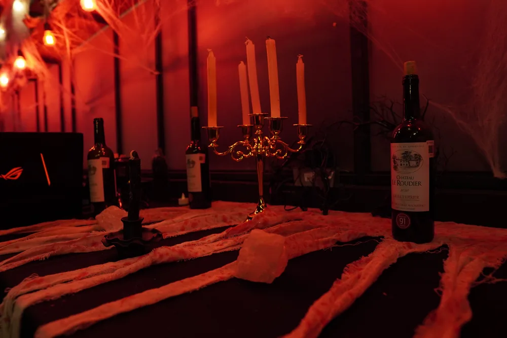 Decoración de Halloween: candelabros y botellas sobre mesa con telarañas