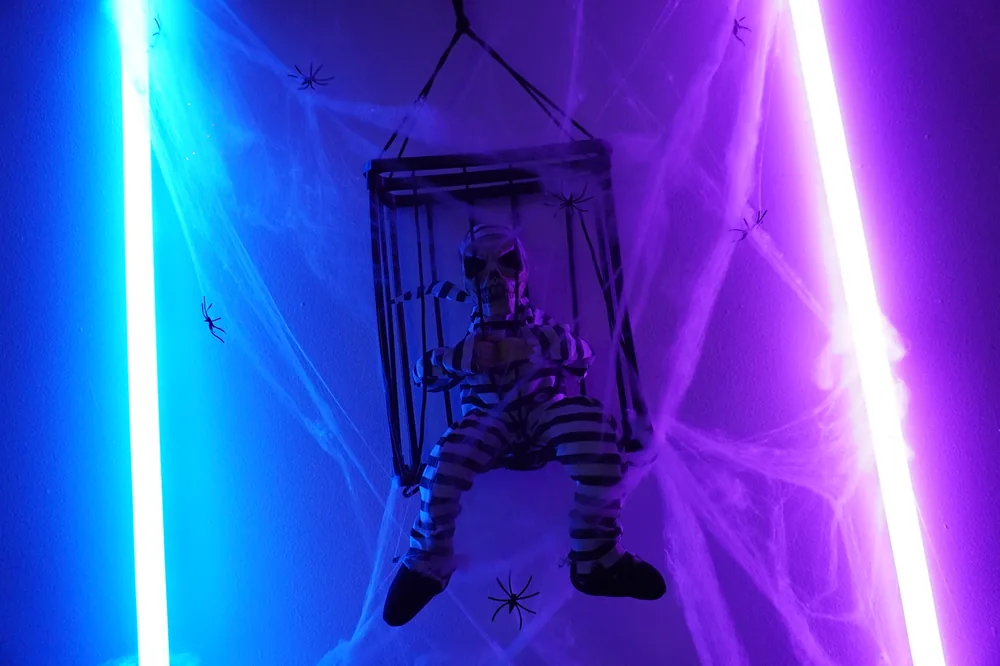 Decoración de Halloween: jaula con esqueleto colgante y luz morada