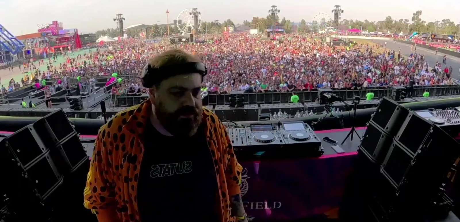 DJ Bonhaus de perfil en cabina con el público del festival al fondo