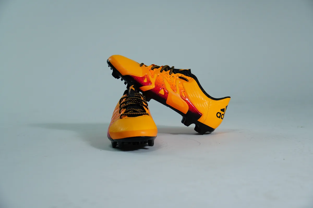 Foto de producto para e-commerce: tacos de futbol naranjas en estudio, toma 22