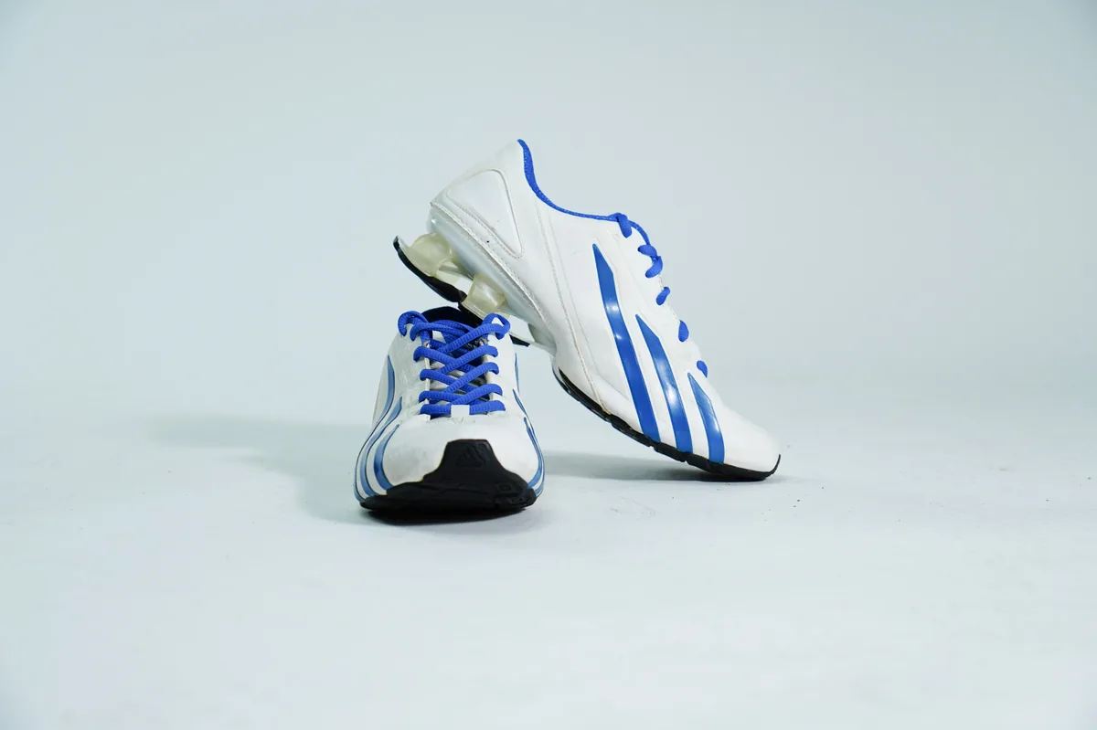 Foto de producto para e-commerce: tenis deportivos blanco con azul en estudio, toma 127