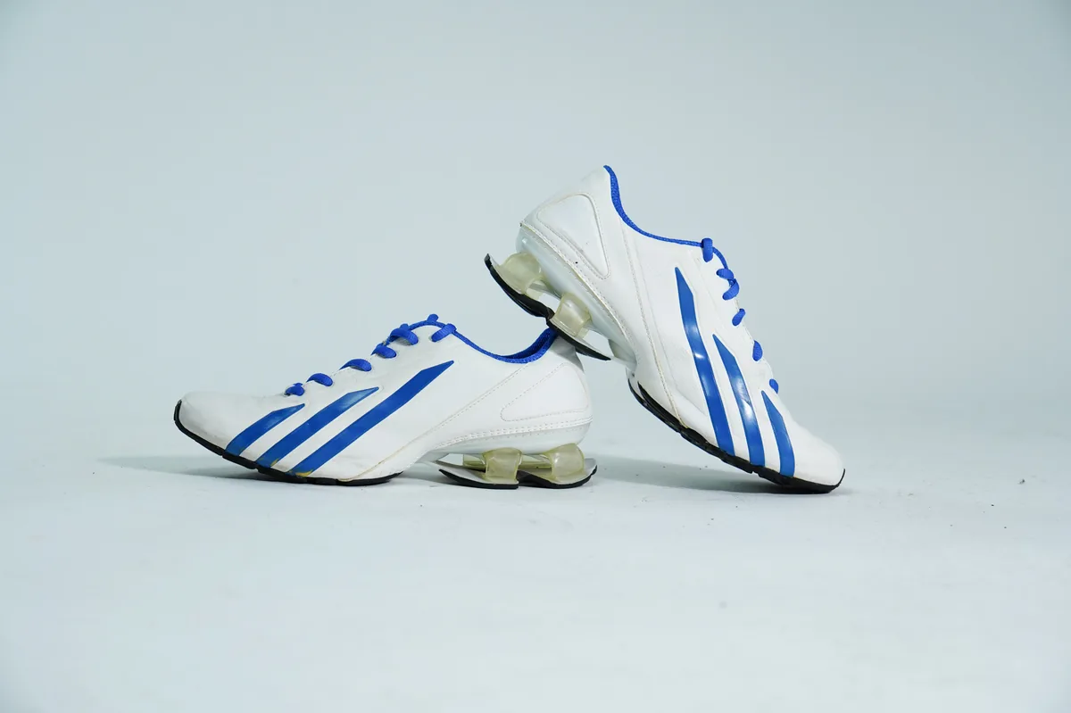 Foto de producto para e-commerce: tenis deportivos blanco con azul en estudio, toma 128
