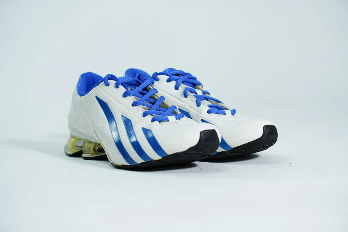 Foto de producto para e-commerce: tenis deportivos blanco con azul en estudio, toma 129