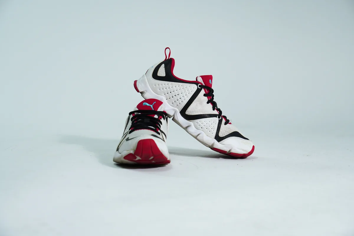 Foto de producto para e-commerce: tenis deportivos blanco con rojo en estudio, toma 100