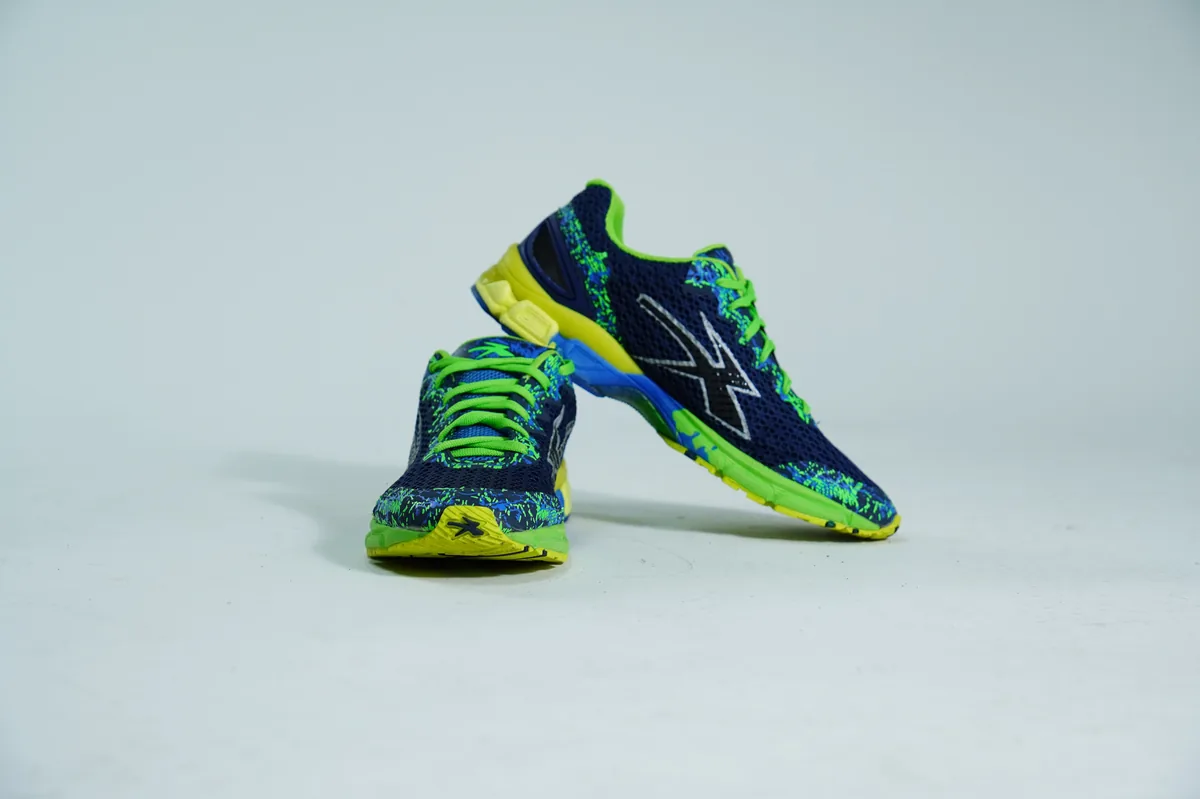 Foto de producto para e-commerce: tenis para correr verde con azul en estudio, toma 109