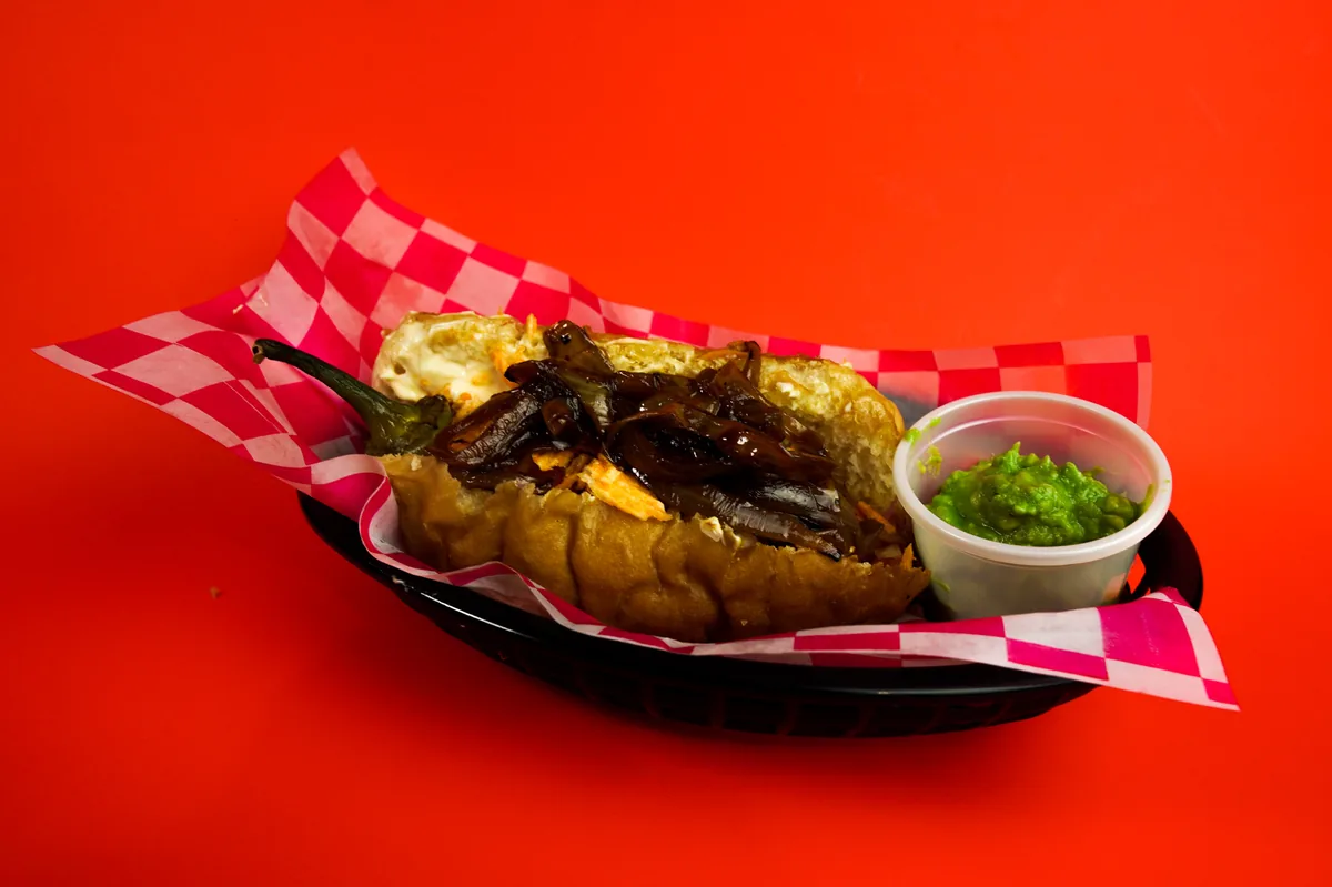 Fotografía de alimentos en estudio: hot dog con guacamole sobre fondo rojo, toma 46