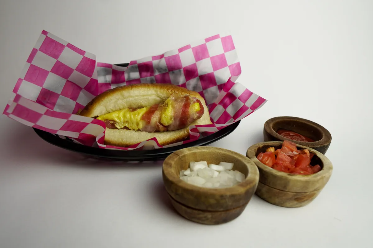 Fotografía de alimentos en estudio: hot dog con salsas sobre fondo blanco, toma 25