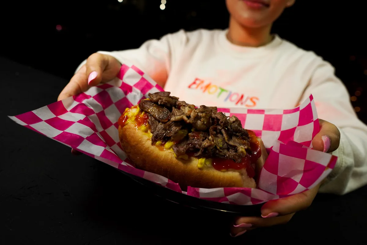 Fotografía de alimentos en estudio: modelo sosteniendo un hot dog en estudio, toma 10