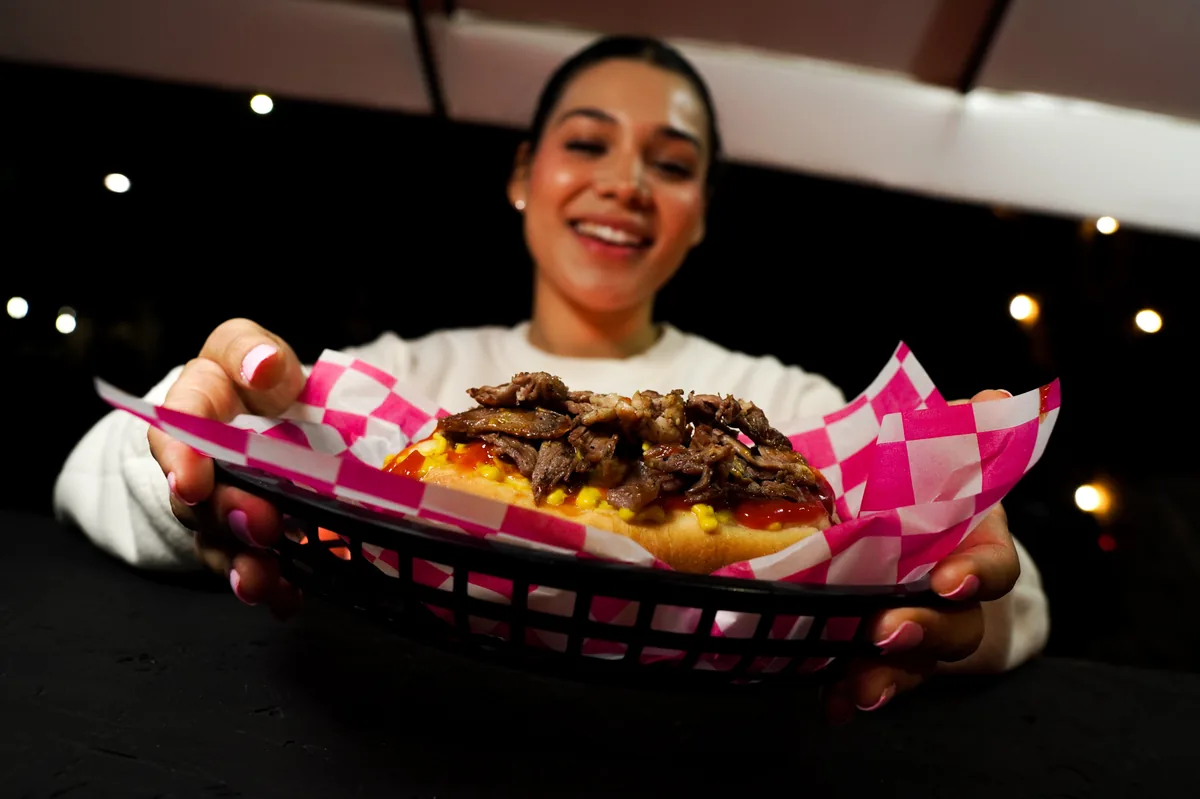 Fotografía de alimentos en estudio: modelo sosteniendo un hot dog en estudio, toma 11