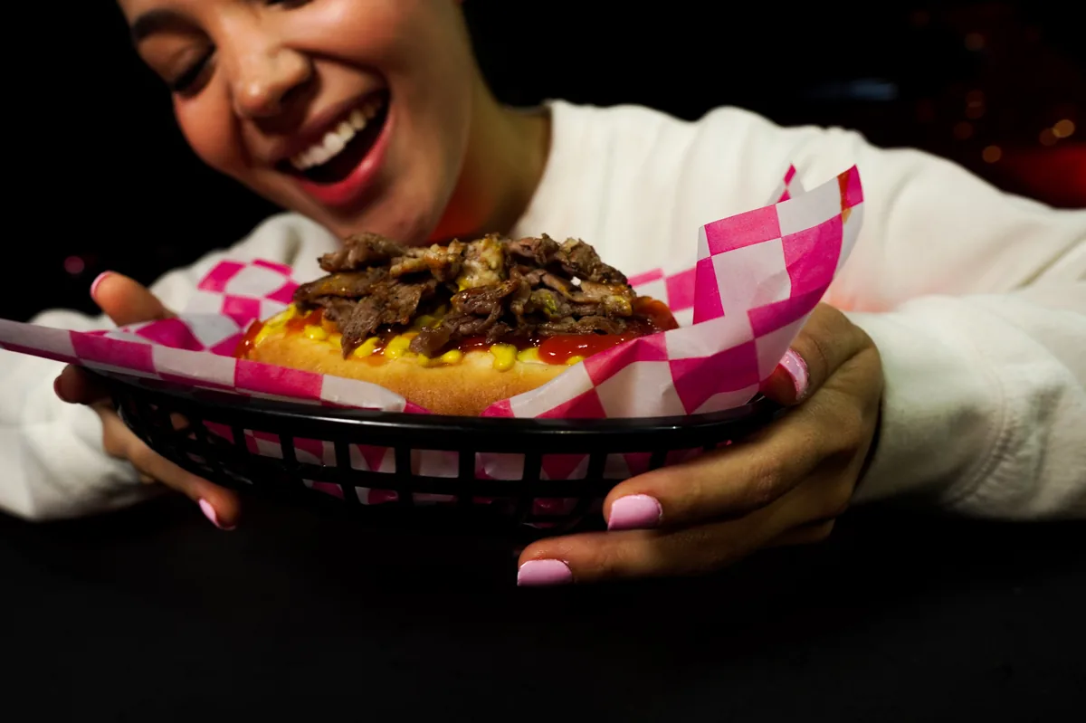 Fotografía de alimentos en estudio: modelo sosteniendo un hot dog en estudio, toma 12