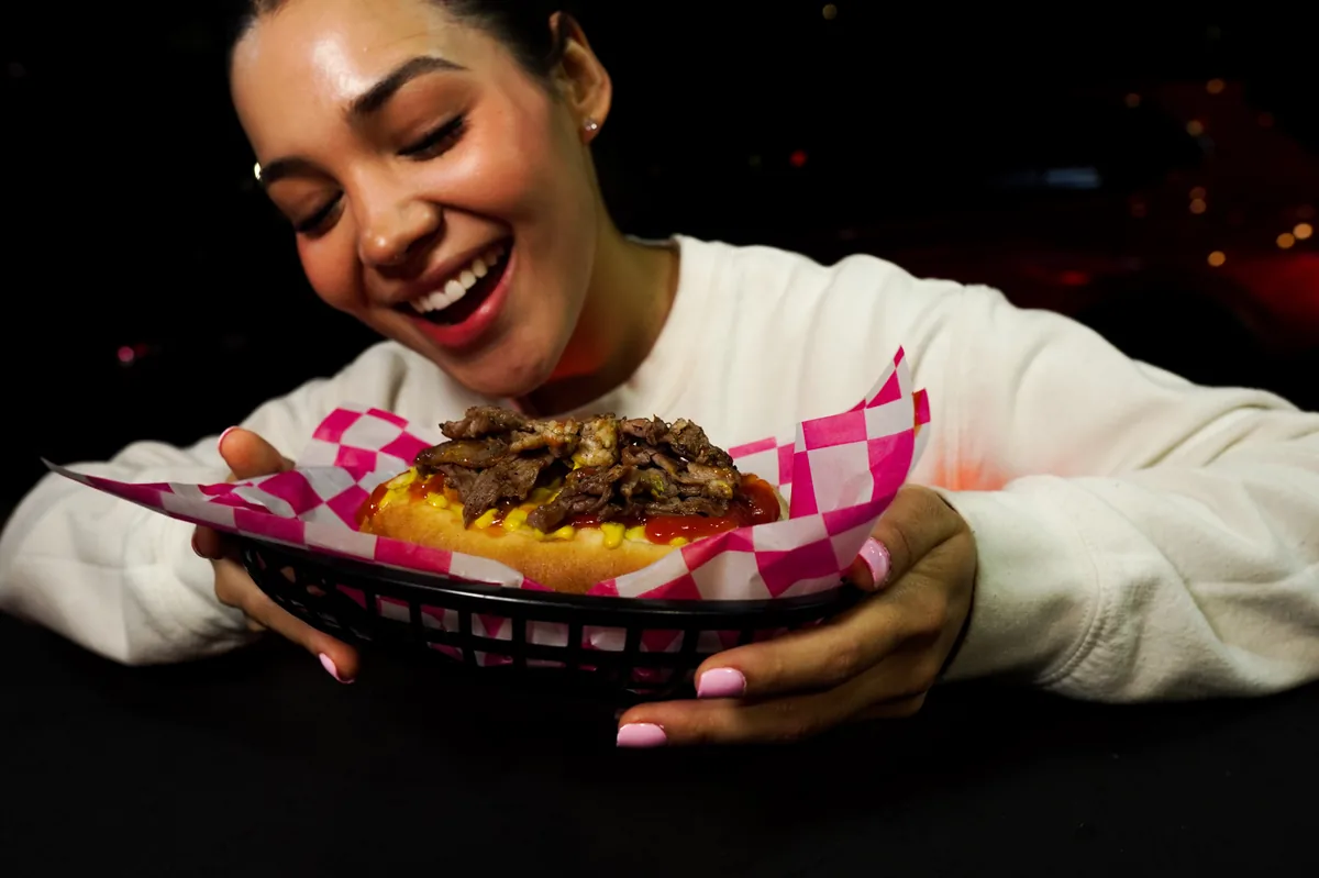 Fotografía de alimentos en estudio: modelo sosteniendo un hot dog en estudio, toma 13