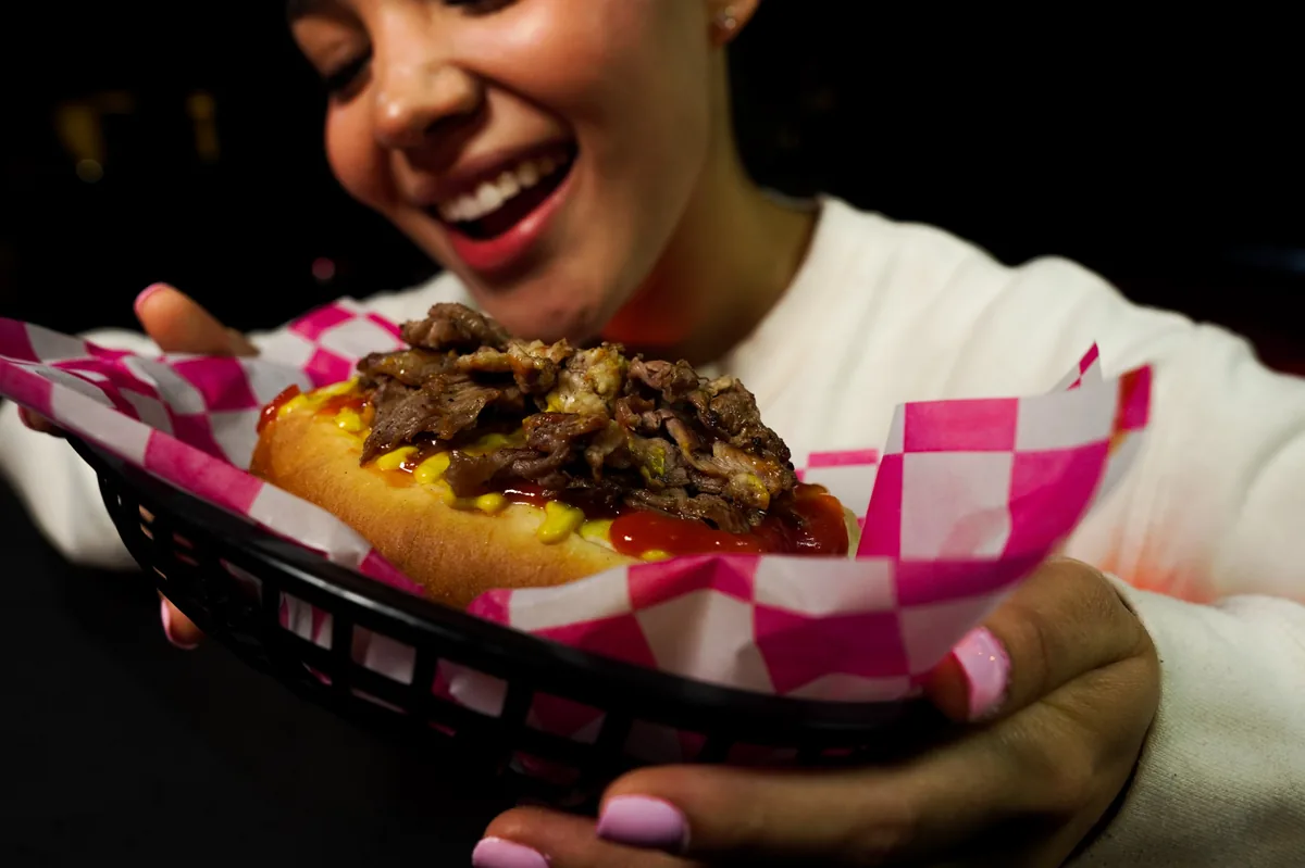 Fotografía de alimentos en estudio: modelo sosteniendo un hot dog en estudio, toma 14
