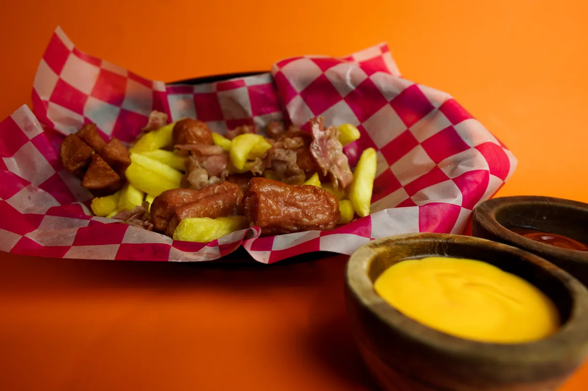 Fotografía de alimentos en estudio: papas con queso y salsas sobre fondo naranja, toma 36