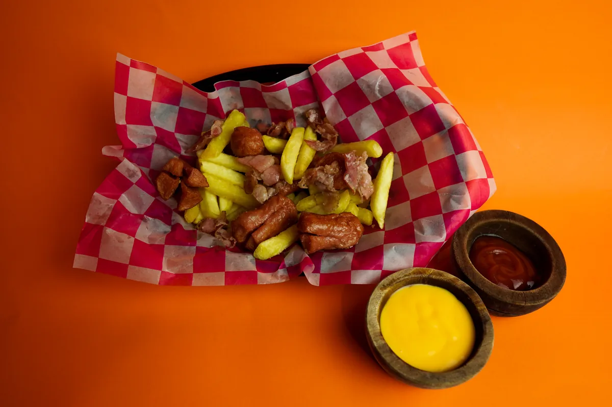 Fotografía de alimentos en estudio: papas con queso y salsas sobre fondo naranja, toma 37