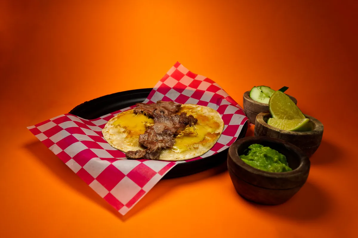 Fotografía de alimentos en estudio: platillo con guacamole sobre fondo naranja, toma 1