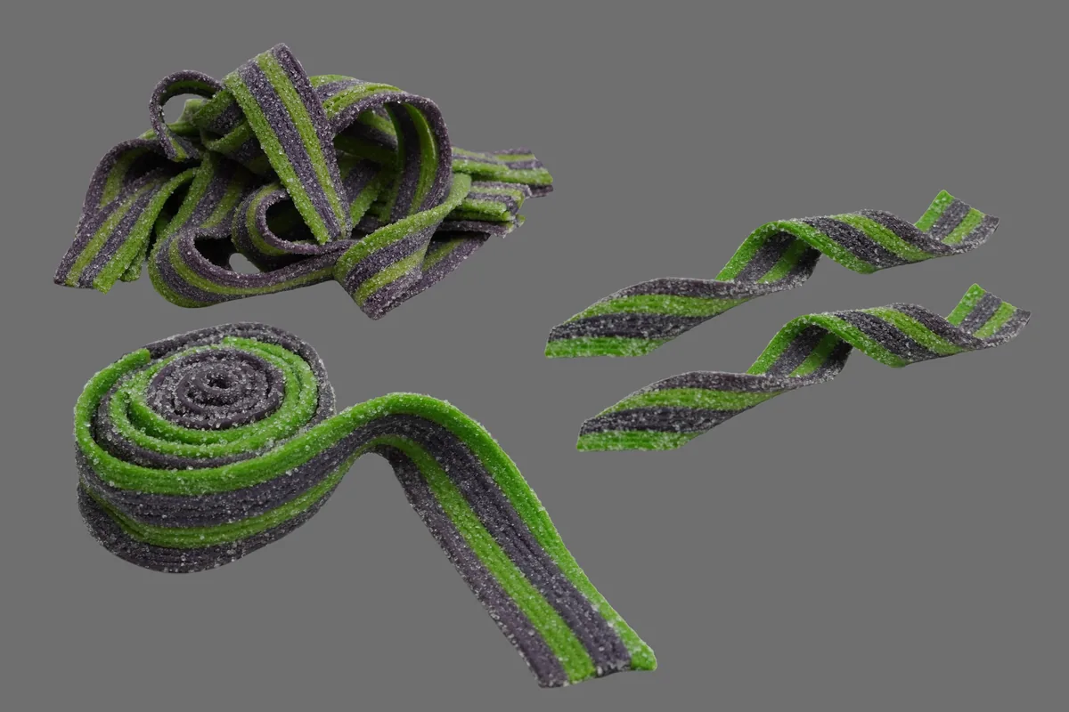 Fotografía de producto de cintas de dulce verde y morado sobre fondo gris de estudio