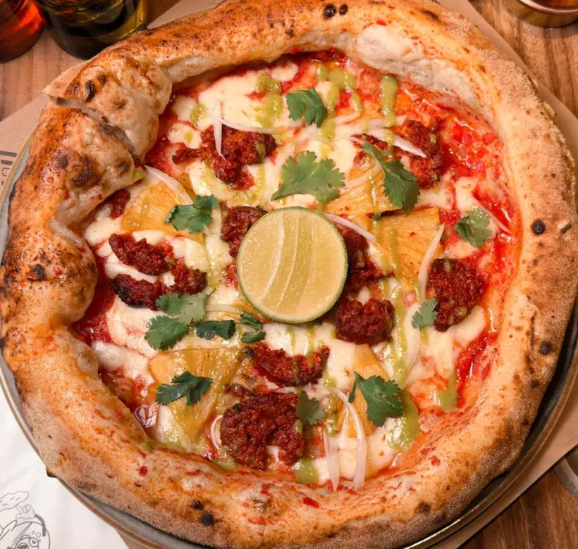 Pizza napolitana con chorizo artesanal, piña tatemada y cilantro
