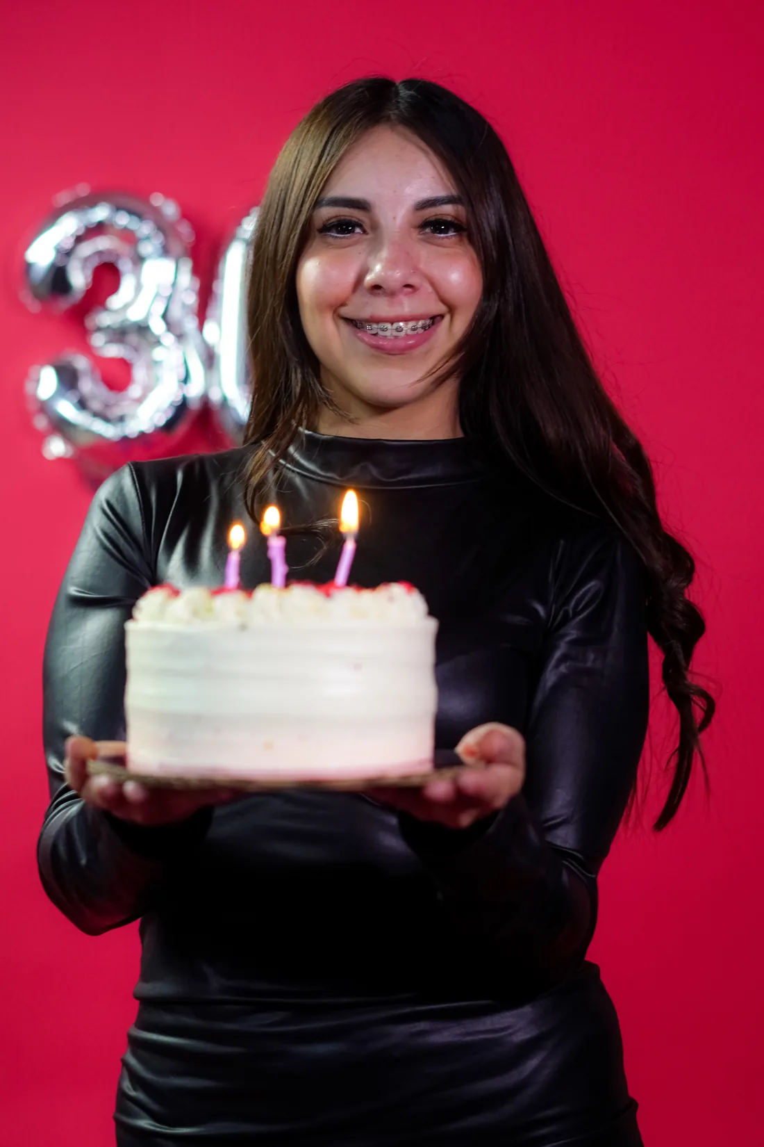 Sesión de fotos de cumpleaños en estudio con vestido negro y números plateados sobre fondo rojo, toma 8
