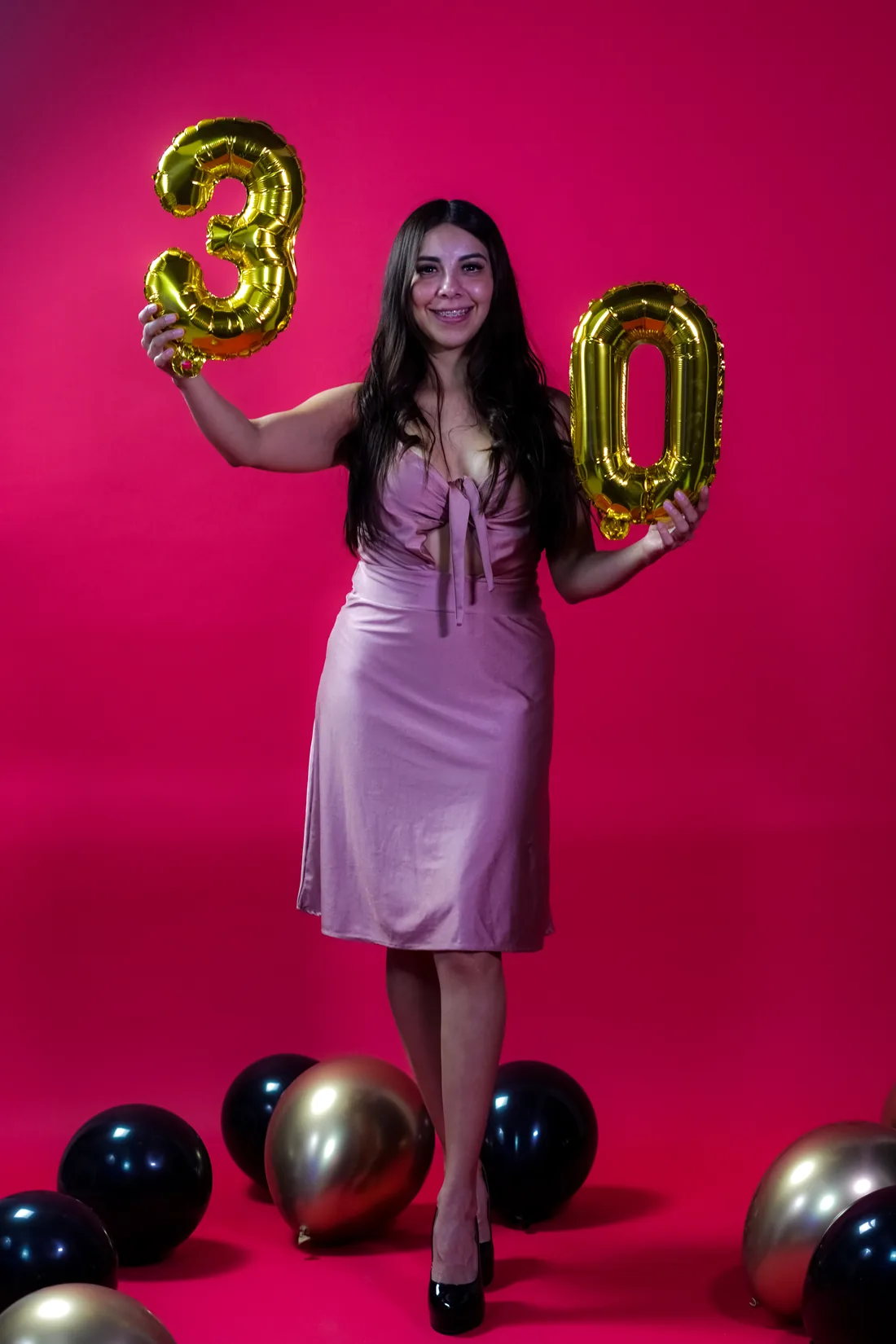 Sesión de fotos de cumpleaños en estudio con vestido rosa y números dorados sobre fondo rosa, toma 10