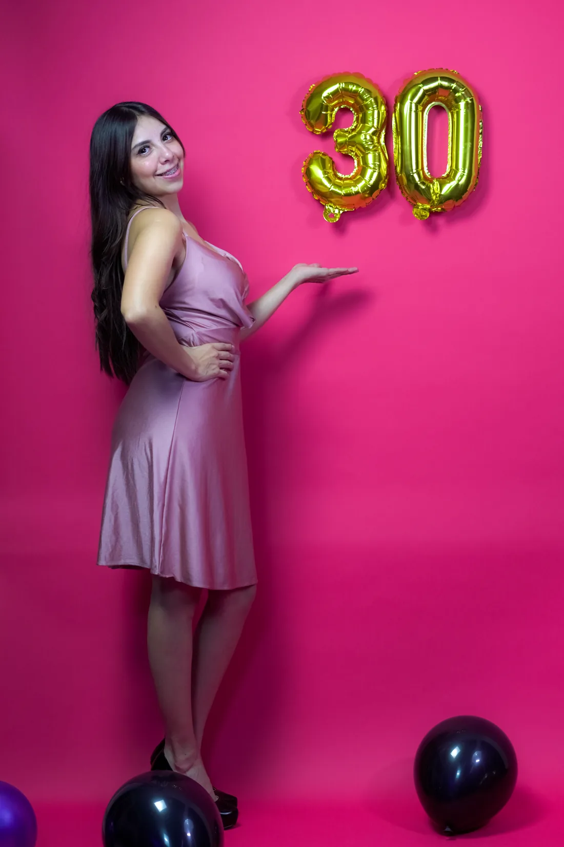Sesión de fotos de cumpleaños en estudio con vestido rosa y números dorados sobre fondo rosa, toma 14