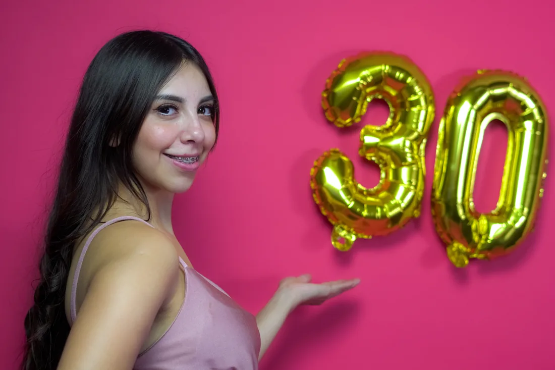 Sesión de fotos de cumpleaños en estudio con vestido rosa y números dorados sobre fondo rosa, toma 16