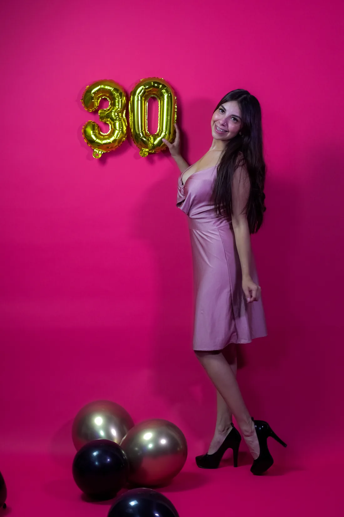Sesión de fotos de cumpleaños en estudio con vestido rosa y números dorados sobre fondo rosa, toma 18