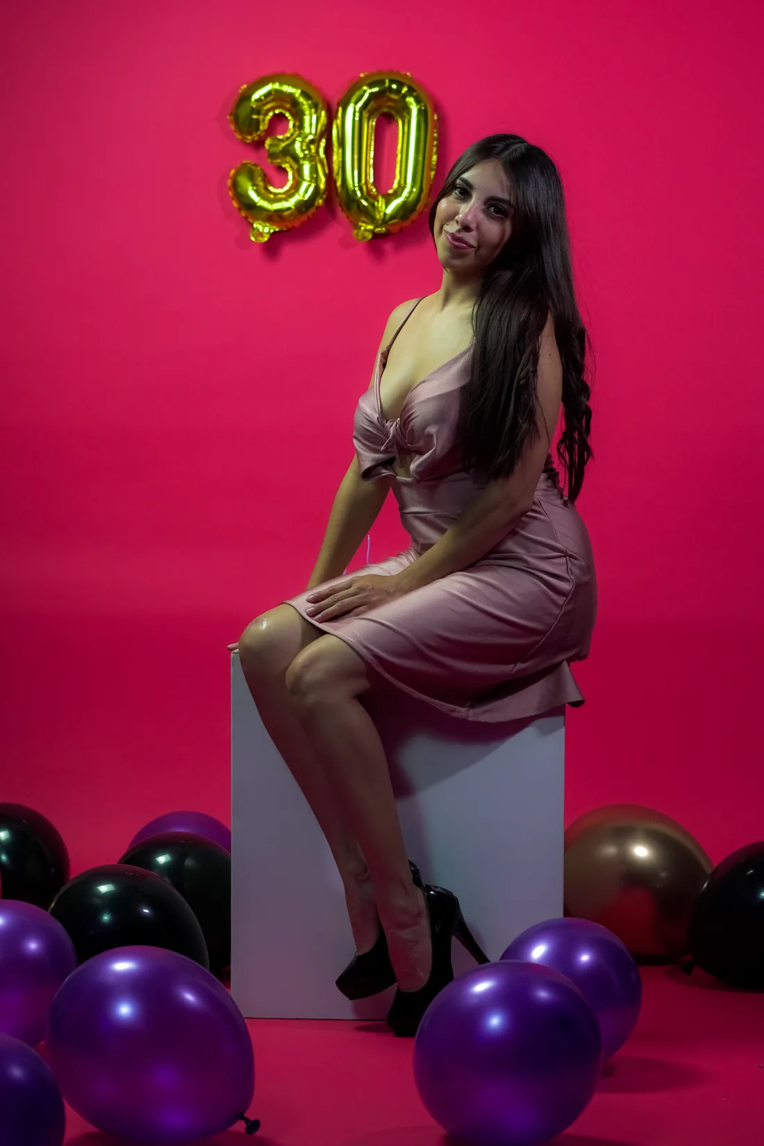 Sesión de fotos de cumpleaños en estudio con vestido rosa y números dorados sobre fondo rosa, toma 27
