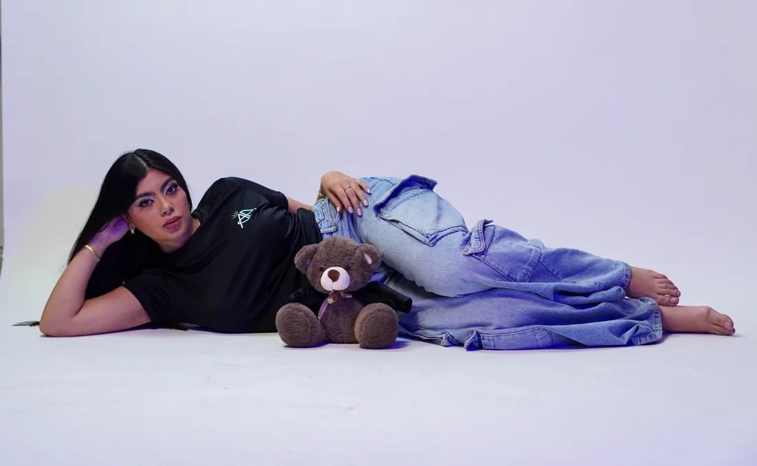 Sesión de fotos en estudio recostada con peluche sobre fondo blanco
