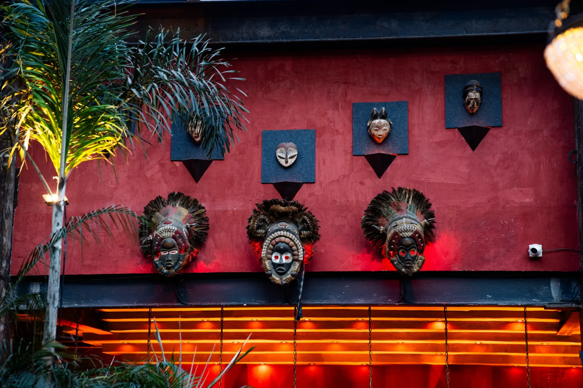 Terraza Roma 11 — muro decorativo con máscaras africanas iluminado