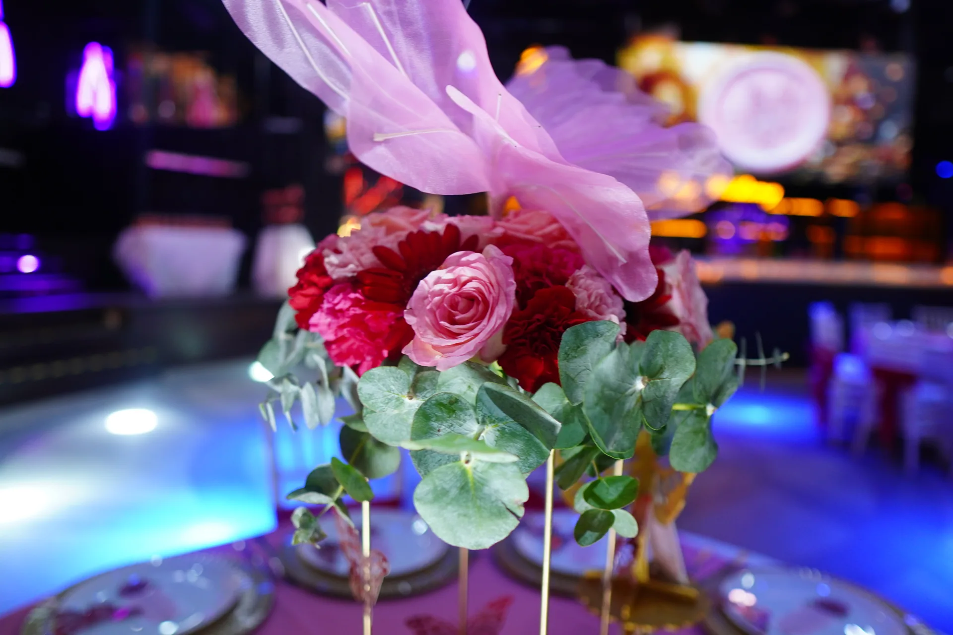 Centro de mesa de XV años con rosas, eucalipto y plumas rosas