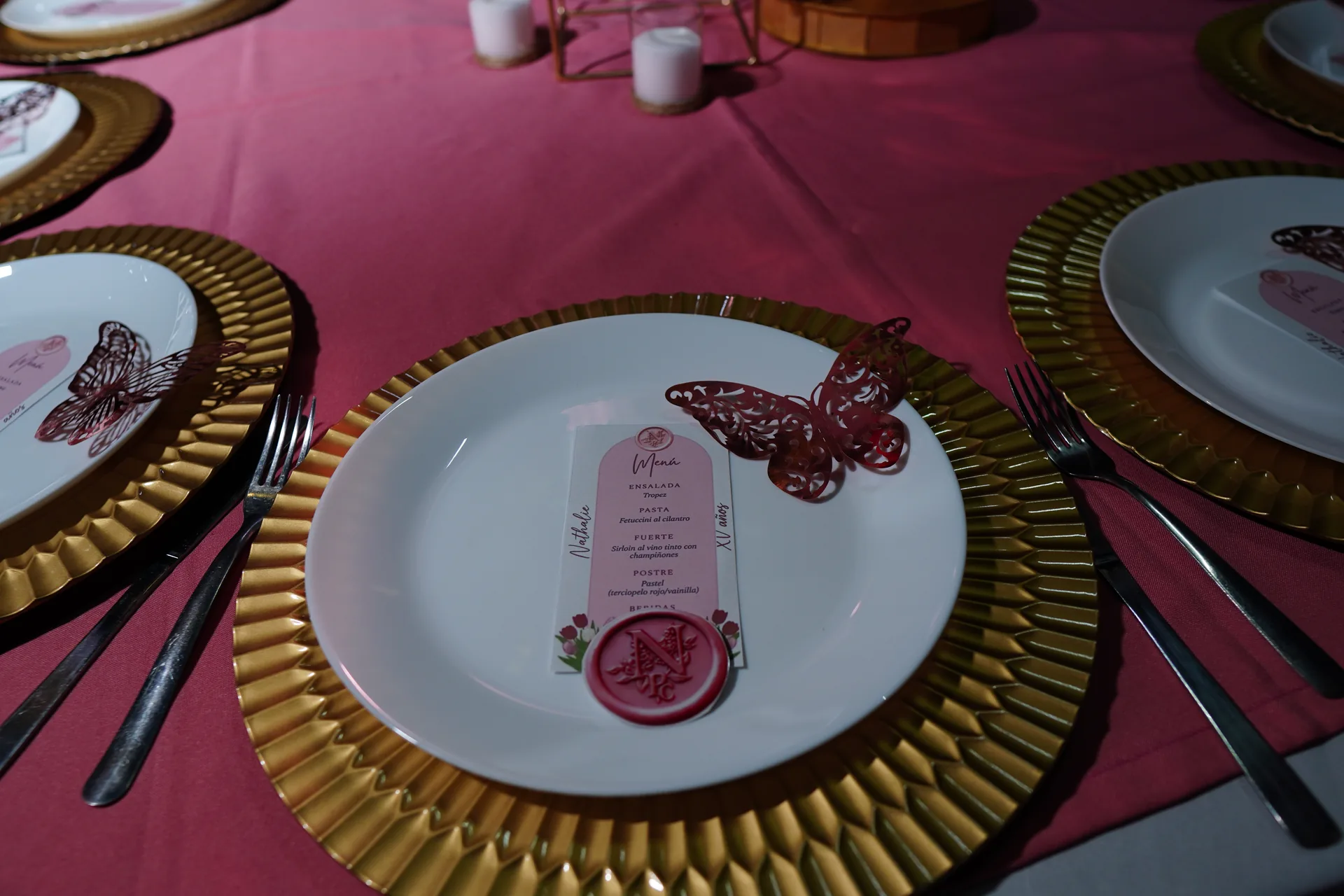 Montaje de XV años: plato base dorado con menú impreso y mariposa